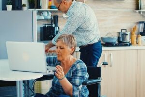 Femme en fauteuil roulant utilisant un ordinateur sur une table trop haute